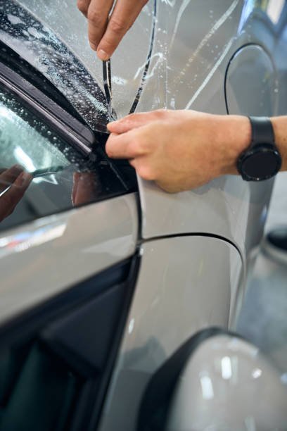 Man cuts off excess film on a car, the process of gluing protective film